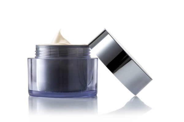 Light brown beauty cosmetic cream in gray glass jar on white background.