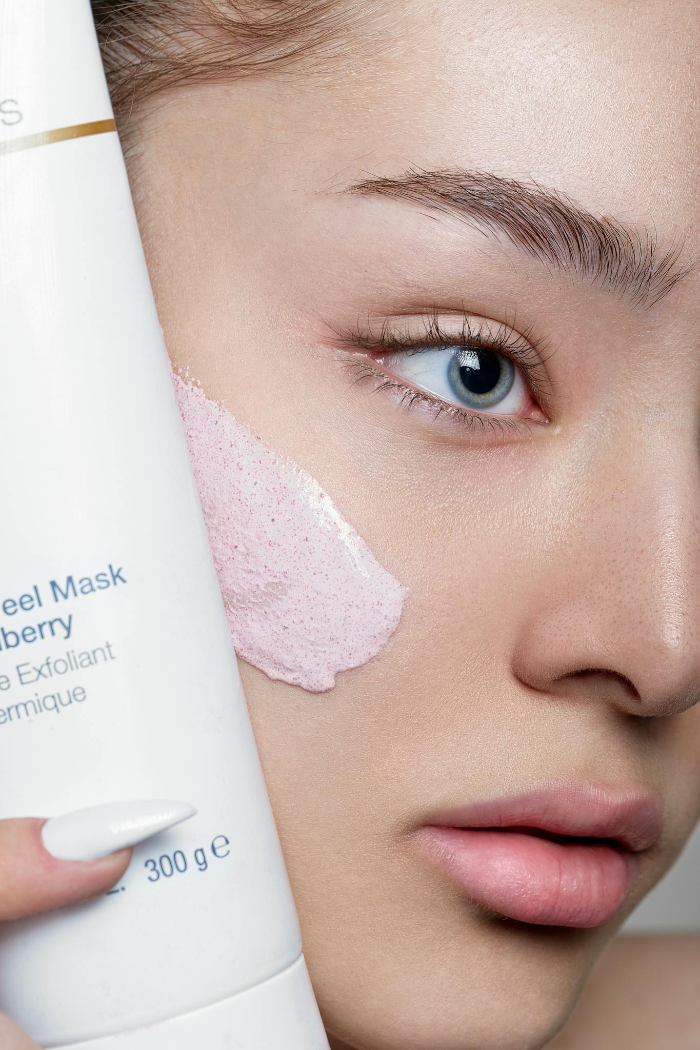 Close-up of a woman applying skincare mask with product visible, showcasing beauty routine.