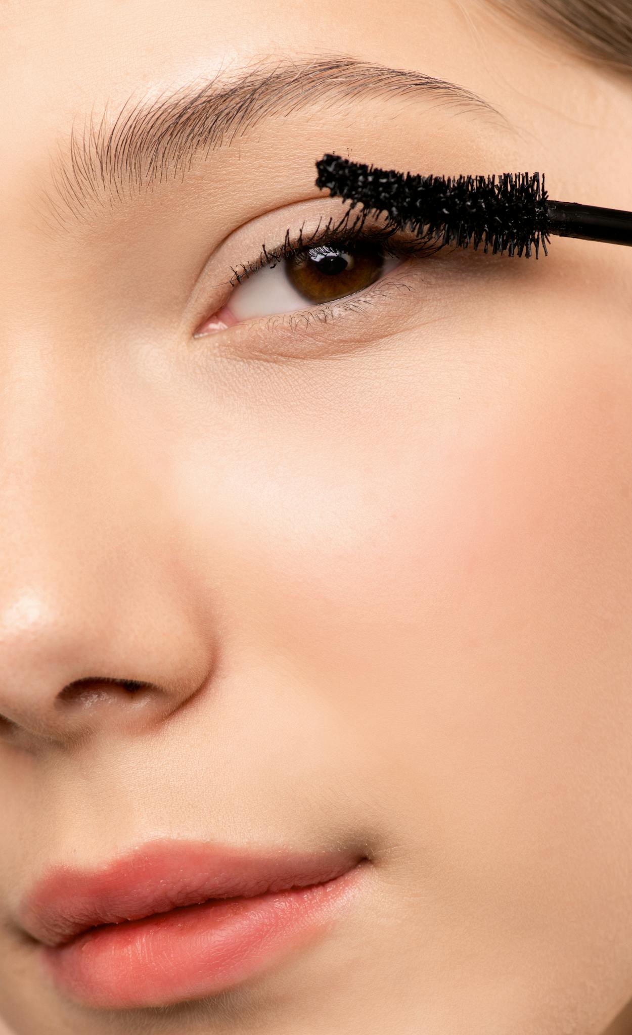 Close-up of a woman's face applying mascara for a natural beauty look.